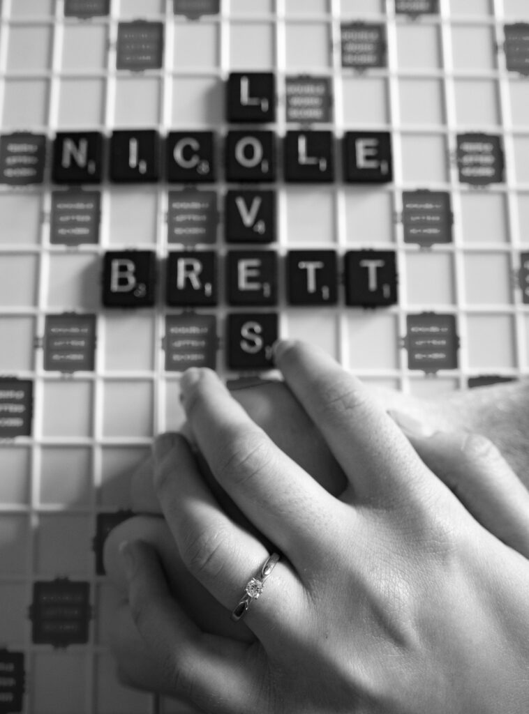 Photo of hands on a scrabble board spelling Brett and Nicole